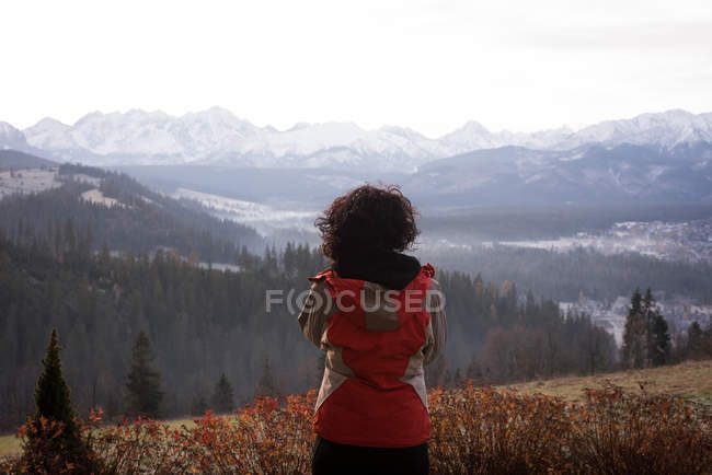 Rear view of woman in warm clothing standing near countryside — Stock Photo