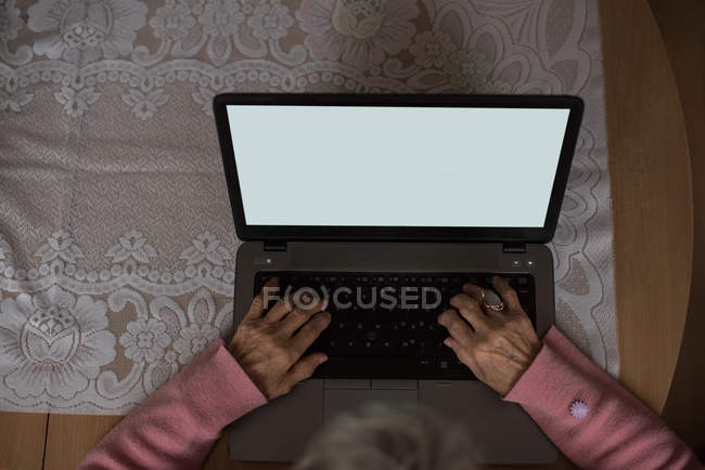 Aktive Seniorin nutzt Laptop zu Hause — Stockfoto