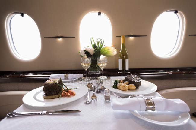 Еда и напитки подаются на столике в частном самолете — стоковое фото