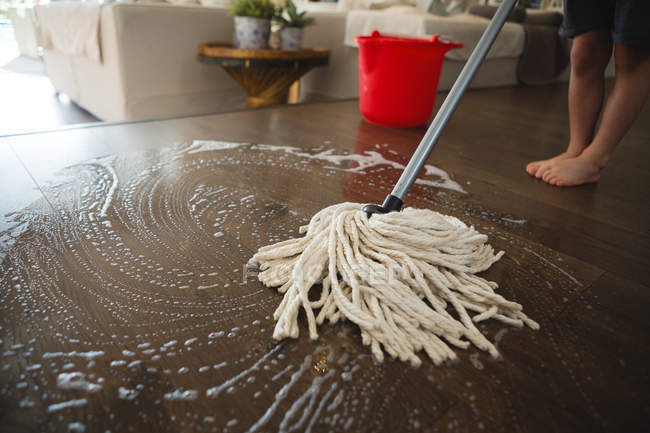 Низька частина хлопчика миє підлогу мопедом вдома — стокове фото