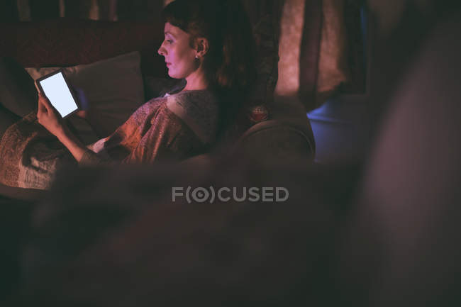 Mulher usando tablet digital no sofá na sala de estar em casa — Fotografia de Stock