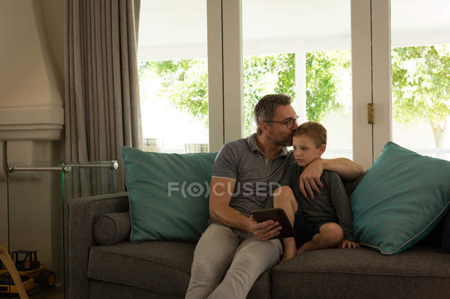 Padre e figlio utilizzano tablet digitale in soggiorno a casa — Foto stock