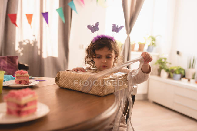 Preschooler girl opening gift box in living room at home. — Stock Photo