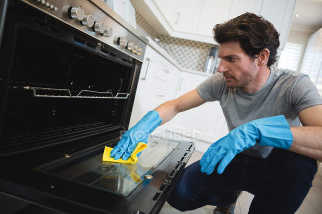 Hombre de limpieza de horno de gas en la cocina en casa - foto de stock