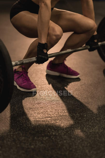 Low section of fit woman exercising with barbell in the studio — Stock Photo