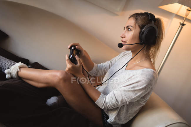 Женщина играет в видеоигру с гарнитурой в гостиной дома — стоковое фото