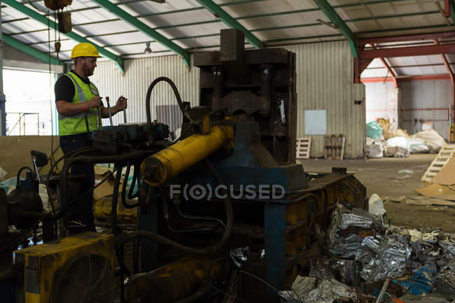Arbeiter in reflektierender Jacke bedient eine Maschine auf dem Schrottplatz — Stockfoto
