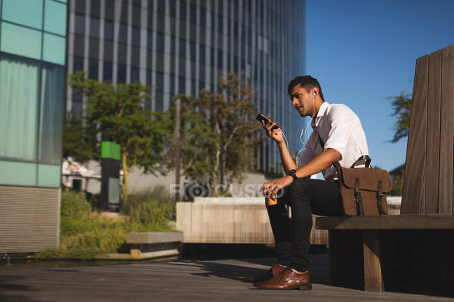 Jungunternehmer hört in Büroräumen auf dem Handy Musik — Stockfoto