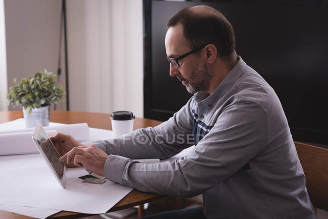 Male executive using digital tablet at desk in office — Stock Photo