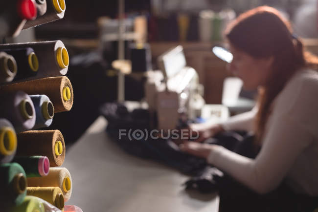 Stoffbündel und Schneiderarbeit im Hintergrund in der Werkstatt — Stockfoto