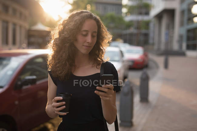 Belle femme utilisant un téléphone mobile par une journée ensoleillée — Photo de stock