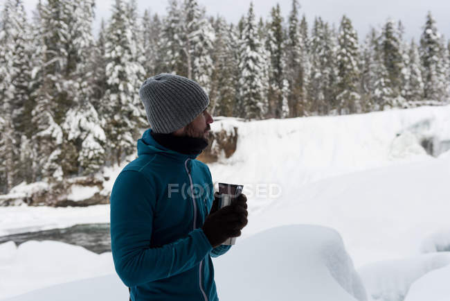Uomo che prende un caffè su un paesaggio innevato durante l'inverno — Foto stock