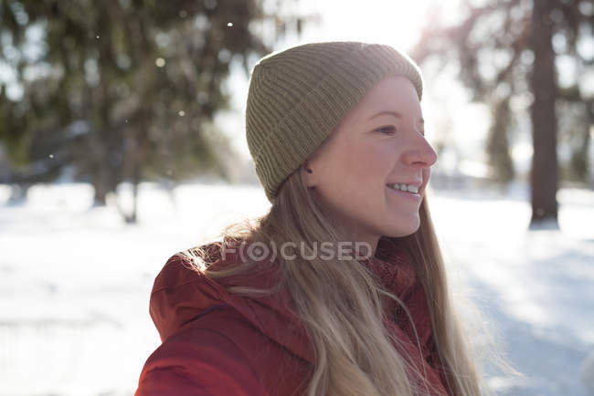 Mujer sonriente de pie en el paisaje cubierto de nieve - foto de stock