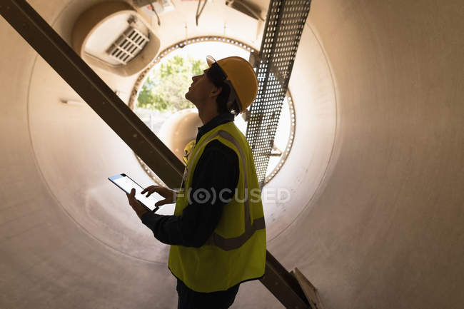 Чоловічий працівник, використовуючи цифровий планшетний при розгляді бетонний тунель на сонячної станції — стокове фото