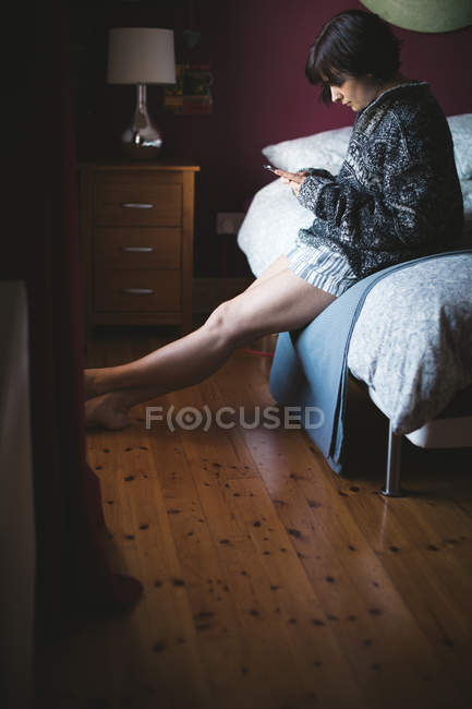 Женщина с мобильного телефона в спальне дома — стоковое фото