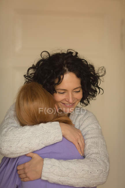 Мати і дочка обіймаються у вітальні вдома — стокове фото