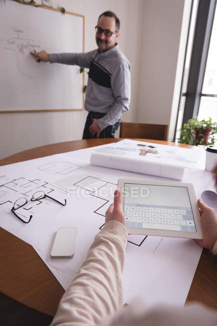 Männliche Führungskraft diskutiert Diagramm auf Whiteboard mit weiblicher Mitarbeiterin im Büro — Stockfoto