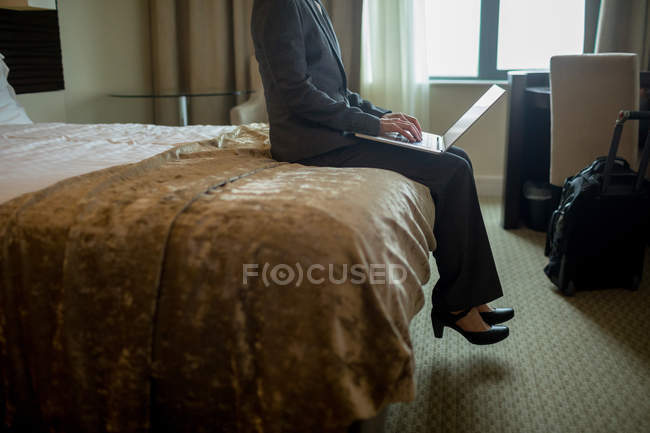 Donna d'affari che utilizza il computer portatile sul letto in camera d'albergo — Foto stock