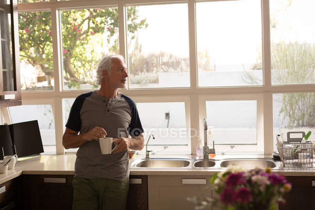 Старший чоловік має каву на кухні вдома — стокове фото