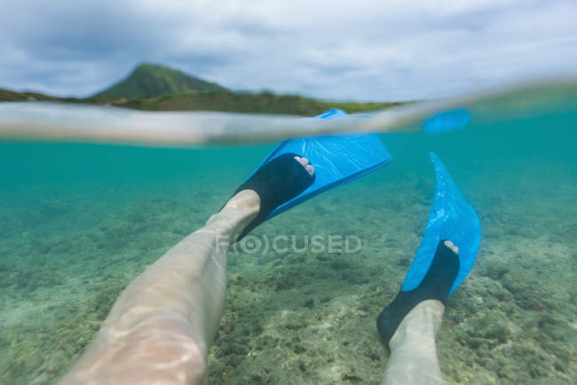 Low section of male legs in swim fins in turquoise sea — Stock Photo