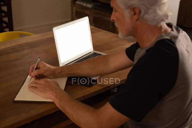 Homme âgé actif écrivant sur un journal intime à la maison — Photo de stock