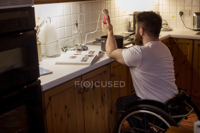Инвалид чинит сковородку на кухне дома — стоковое фото