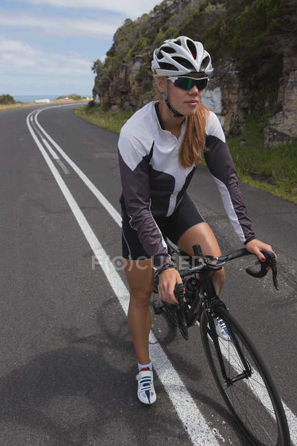Feminino motociclista com mountain bike de pé na estrada em um dia ensolarado — Fotografia de Stock