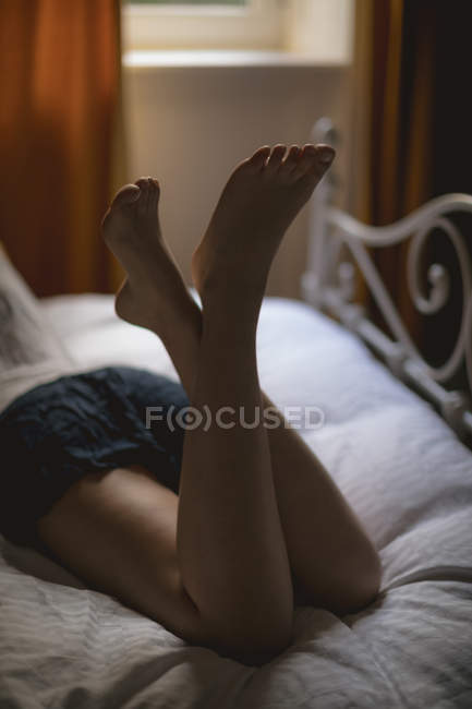 Vista posteriore della donna sdraiata sul letto a casa — Foto stock