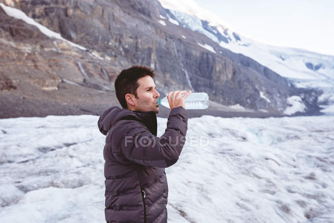 Vista lateral del hombre beber agua de la botella de agua - foto de stock