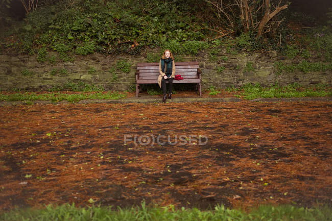 Вдумлива жінка сидить на лавці в парку — стокове фото