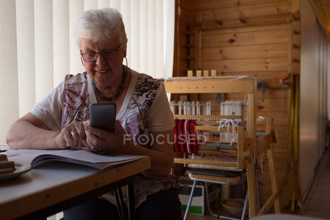 Donna anziana attiva che utilizza il telefono cellulare in negozio — Foto stock