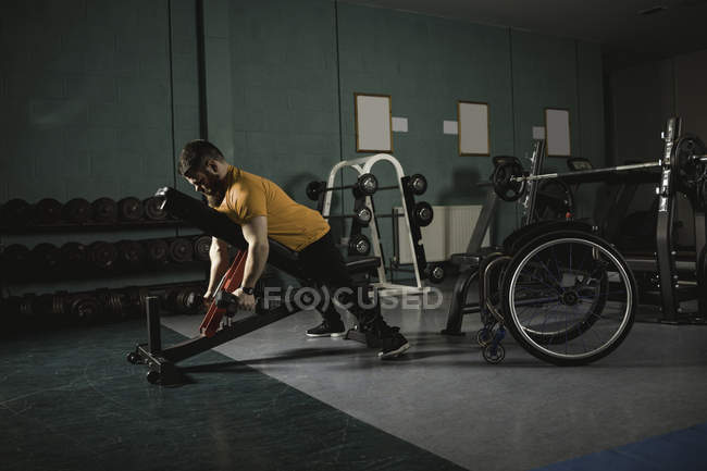 Uomo handicappato che si allena con i manubri sulla panca in palestra — Foto stock