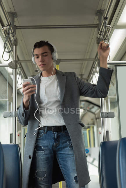 Homem na moda ouvindo música em fones de ouvido enquanto viaja em ônibus — Fotografia de Stock