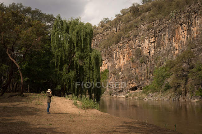 Femme debout près du lac par une journée ensoleillée — Photo de stock