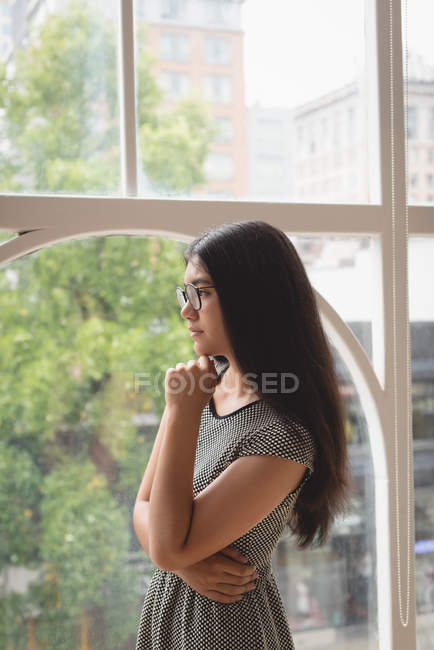 Продумана жінка-виконавця дивиться через вікно в творчому офісі — стокове фото