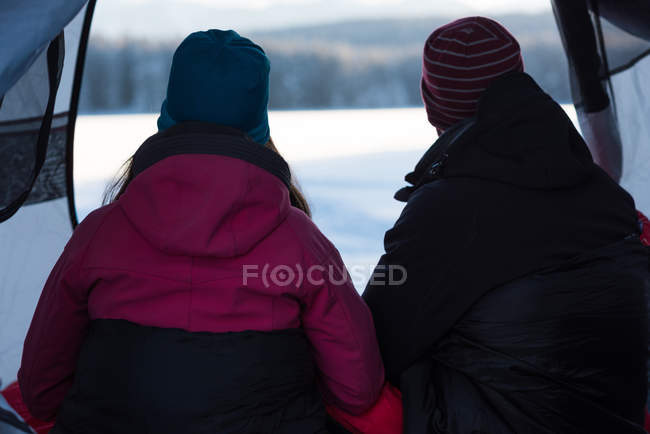 Rückansicht des Paares, das zusammen im Zelt sitzt und die Aussicht betrachtet. — Stockfoto