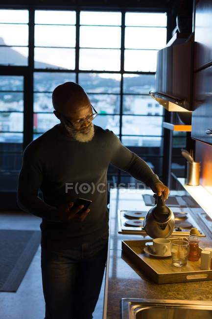 Senior man pouring coffee into cup at kitchen in home — Stock Photo