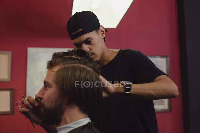 Homem recebendo seu cabelo aparado com tesoura na barbearia — Fotografia de Stock