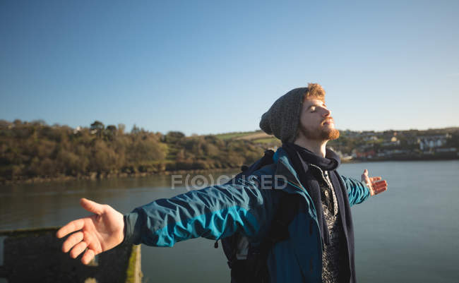 Giovane escursionista maschio in piedi con le braccia tese in campagna — Foto stock
