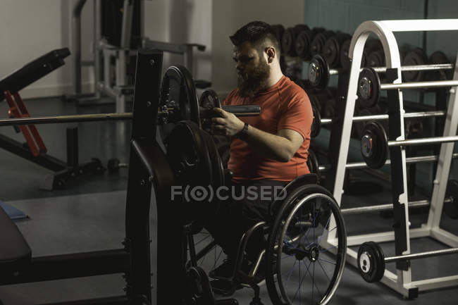 Handicapped man adjusting barbell in gym — Stock Photo