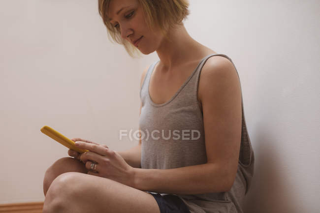 Beautiful woman using mobile phone at home — Stock Photo