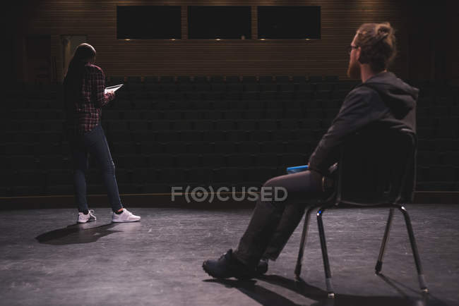 Female actress reading script while male actor watching on stage at theatre. — Stock Photo