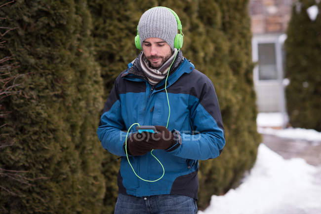 Mann hört im Winter Musik auf Handy. — Stockfoto