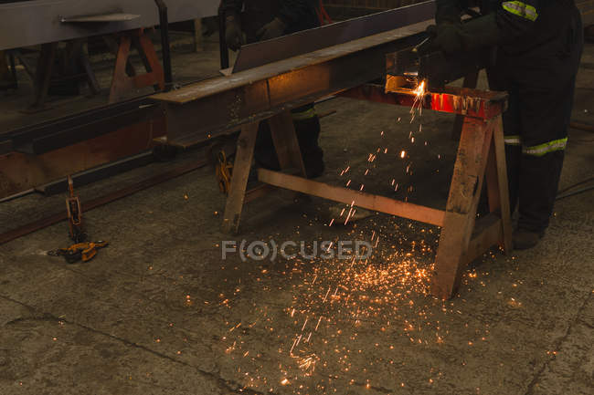 Low section of welder repairing metal frame in workshop — Stock Photo