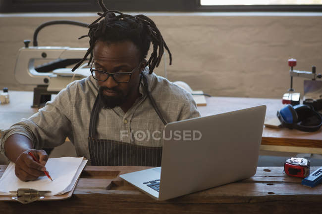 Escrita de carpinteiro na área de transferência ao usar o laptop na oficina — Fotografia de Stock