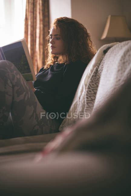Woman reading a book in living room — Stock Photo