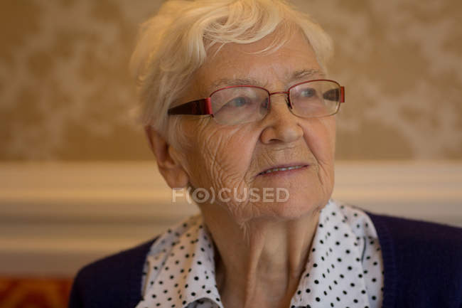 Femme âgée réfléchie souriant à la maison — Photo de stock