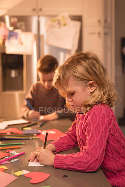 Девочка и мальчик рисуют дома на бумаге — стоковое фото