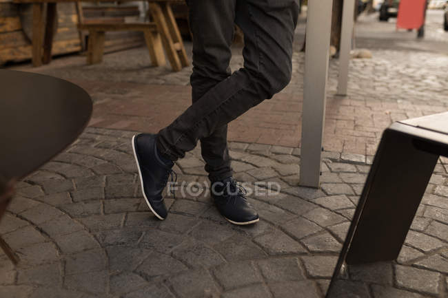 Baixa seção de homem casual em pé no café pavimento — Fotografia de Stock