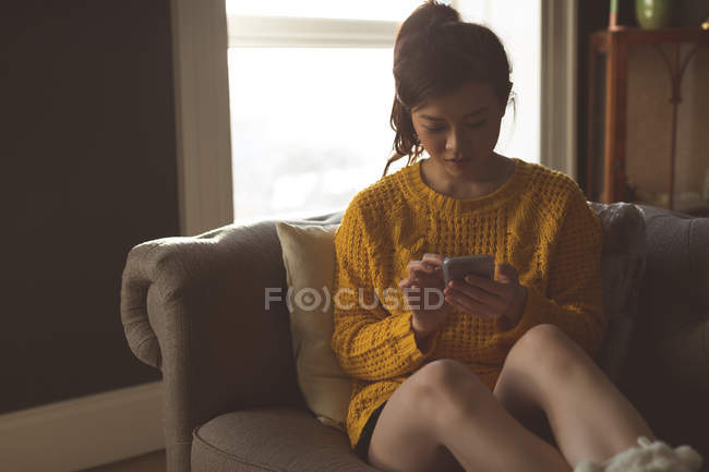 Женщина с мобильного телефона в гостиной на дому — стоковое фото